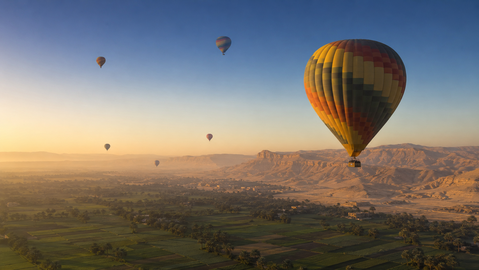 Hot air balloons floating above Luxor's fields and western hills at sunrise